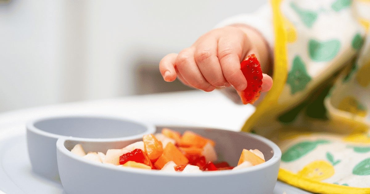 Macro close up of baby hand with a piece of fruits