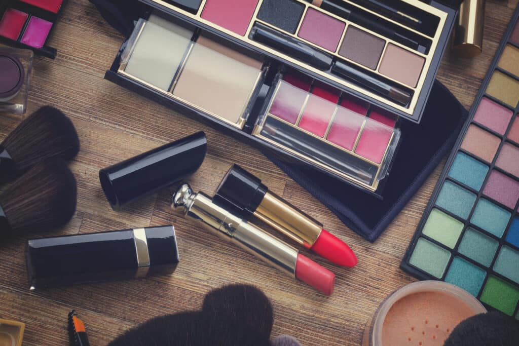 set of brushes, lipsticks, maskara, eye shadows and powder on wood, retro toned
